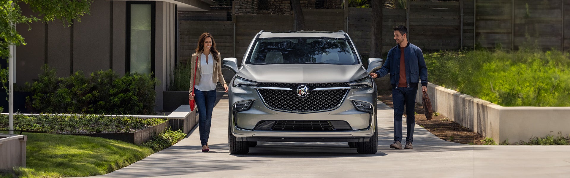 man and woman standing near silver Buick Enclave
